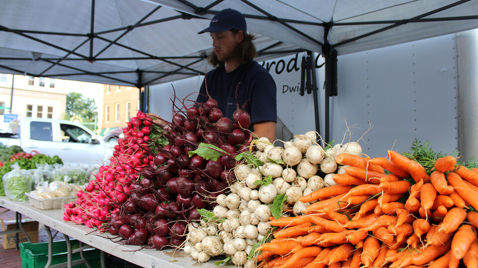 An employee of Pekarek’s Produce, from Dwight, Nebraska, sets up a table to sell produce at the Haymarket Farmers Market in Lincoln.