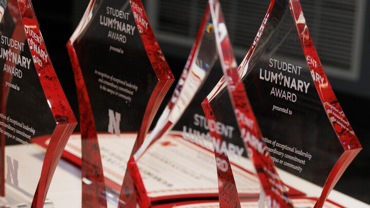 Red glass awards shaped like stars, labeled "Student Luminary Award," arranged on a table.