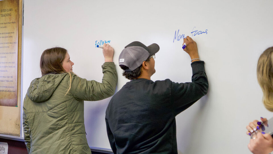 Students writing on a whiteboard.