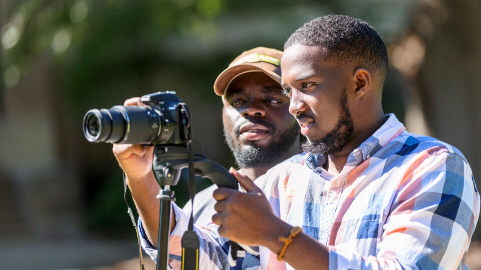 Students learning how to take a picture with a camera.